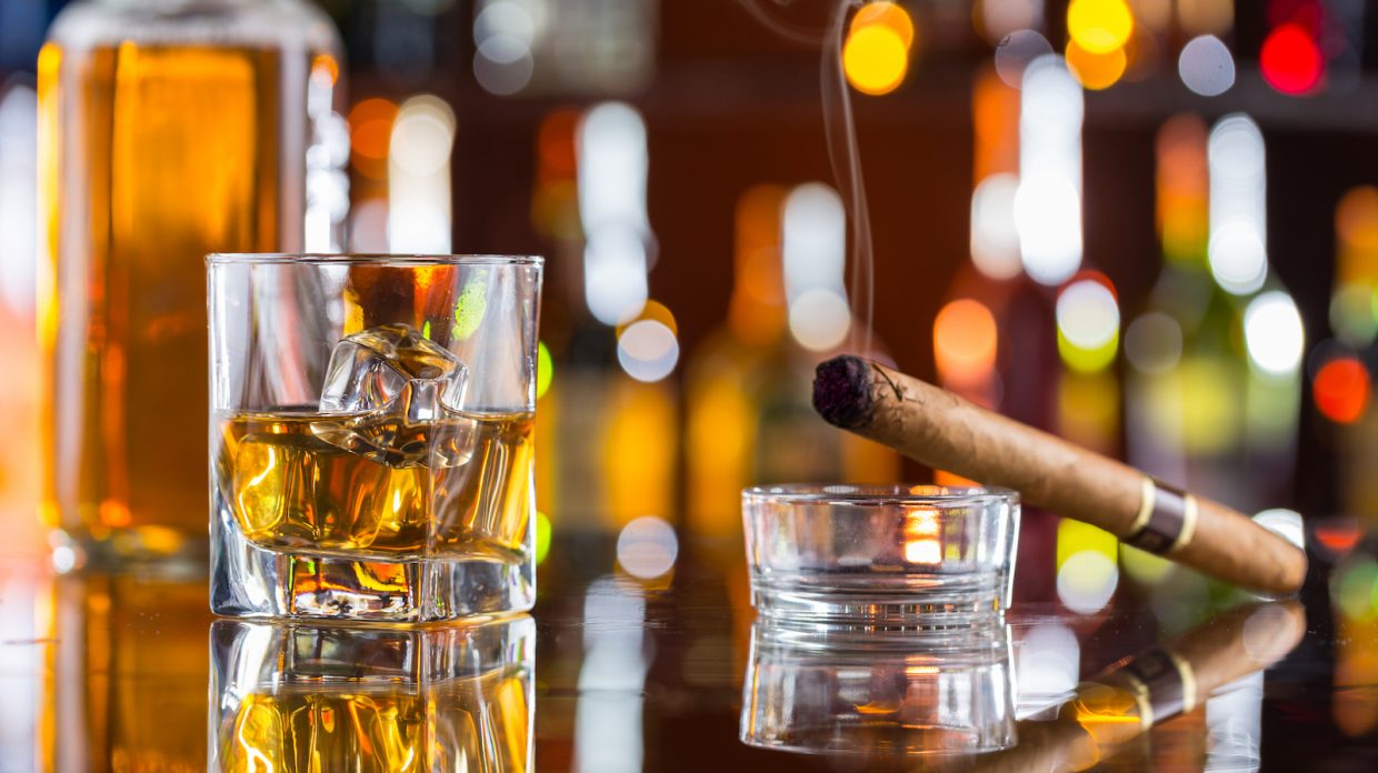 Whiskey drink with smoking cigar on bar