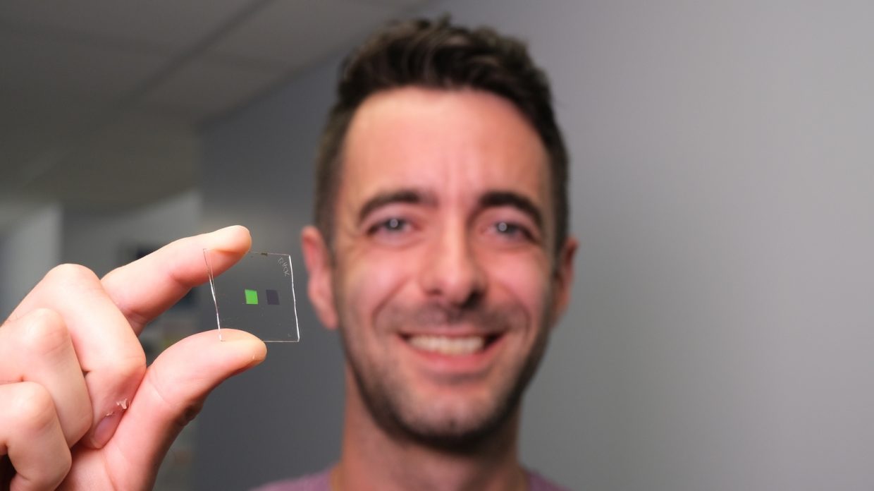 Scottish researcher Alisdair Clark holding a transparent square about 1 inch by one inch