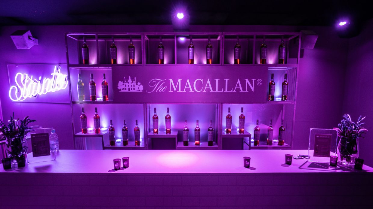 Purple light bathing a bar with The Macallan and bottles of whisky in the background
