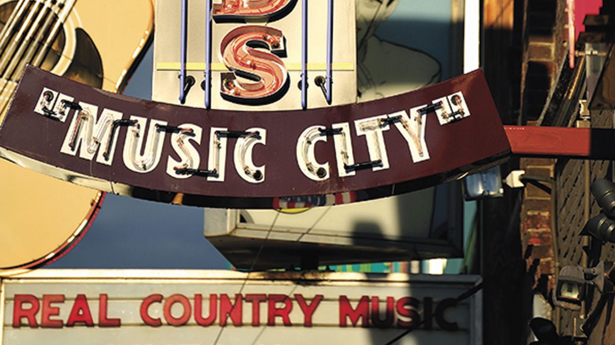 Signs for various music venues in Nashville, Tennessee grace the sidewalks, including one, in view, that says "Music City."