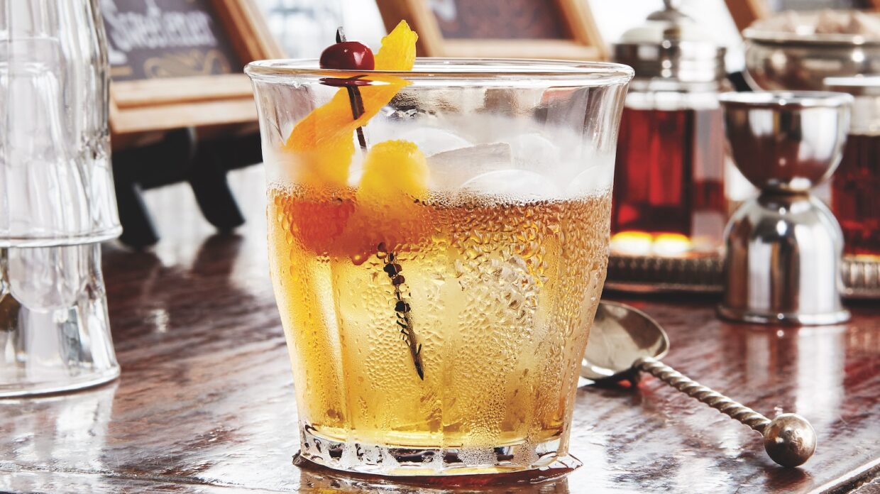 An Old Fashioned in a whiskey glass, showing signs of condensation.