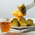 Glass of whisky with sliced pickles and biscuits