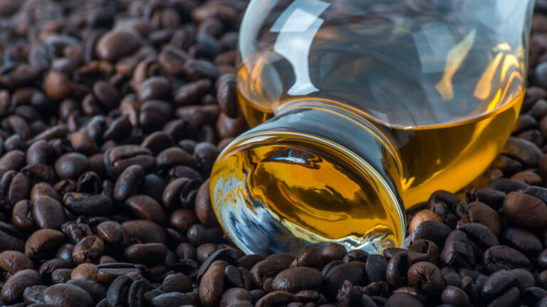 A whisky bottle sits atop coffee beans.