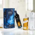 Johnnie Walker Blue Label Legendary Eight and John Walker & Sons Celebratory Blend bottles and cartons on a table with glasses of scotch