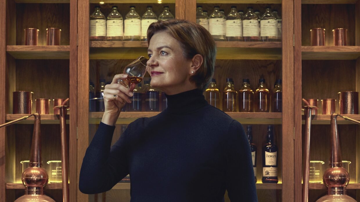 A woman noses a whiskey glass inside a blending room.