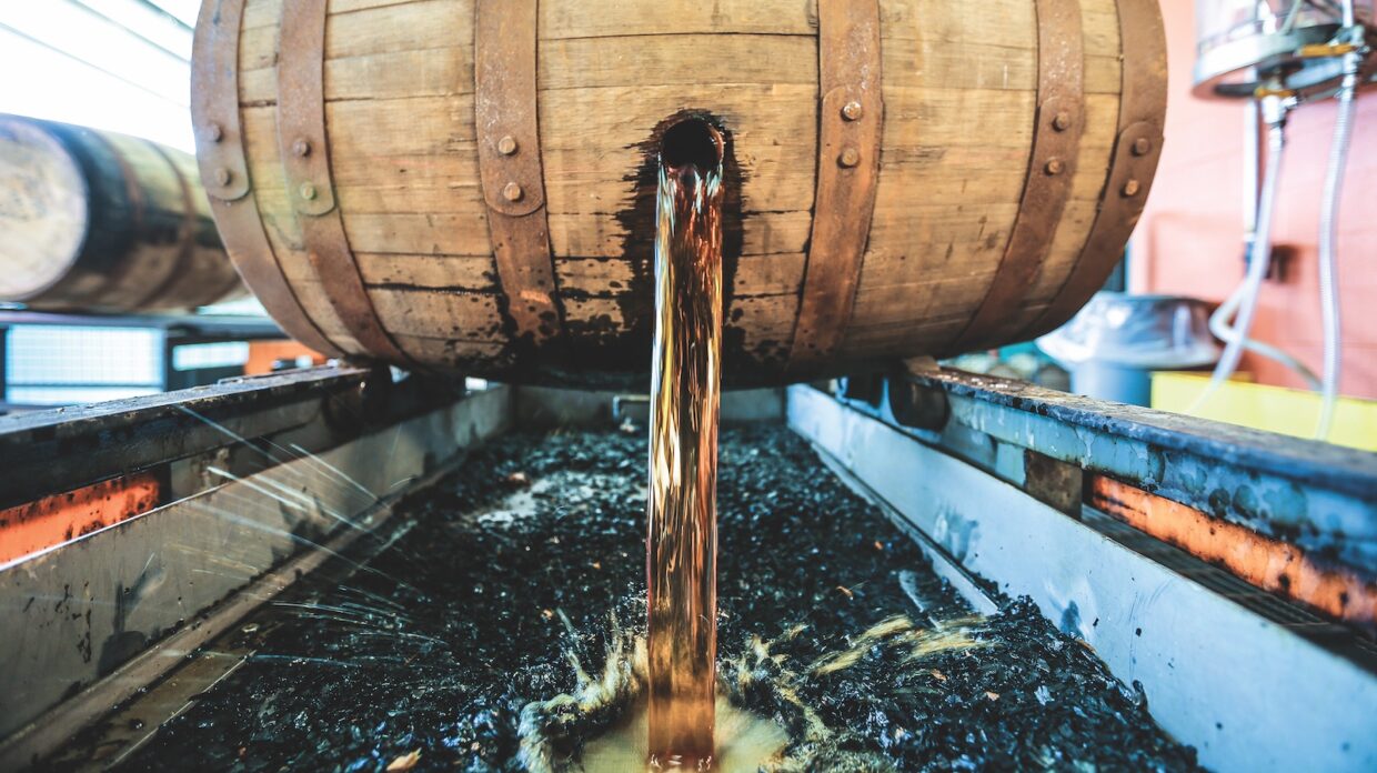 a barrel pouring whiskey through its bunghole into a trough