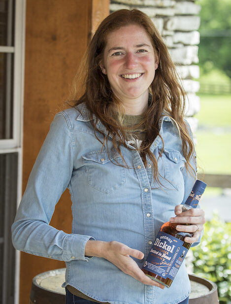 A woman poses with a bottle of whiskey.