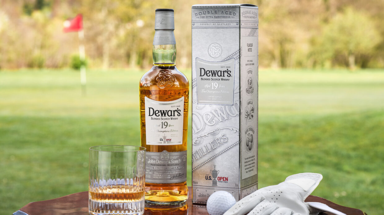 Whisky bottle and glass, half ball and gloves, on a golf course