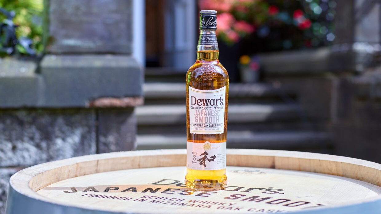 Bottle of scotch sits on top of a barrel