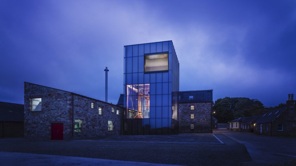 Glass stillhouse lit up at night
