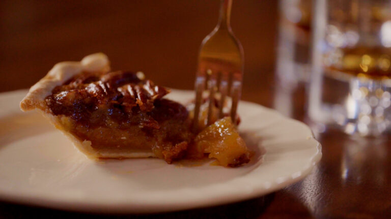 A fork cuts into a piece of pecan pie