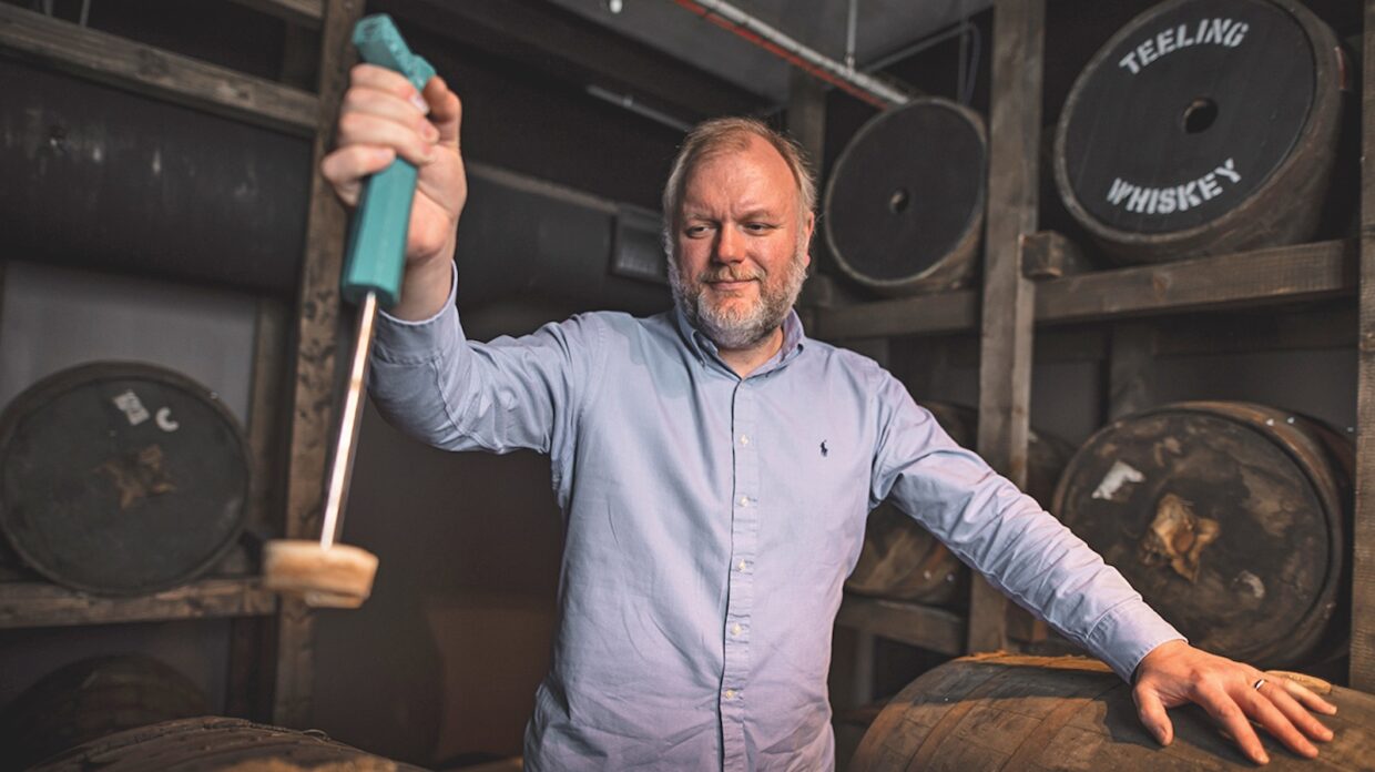 A man uncorks a whiskey barrel