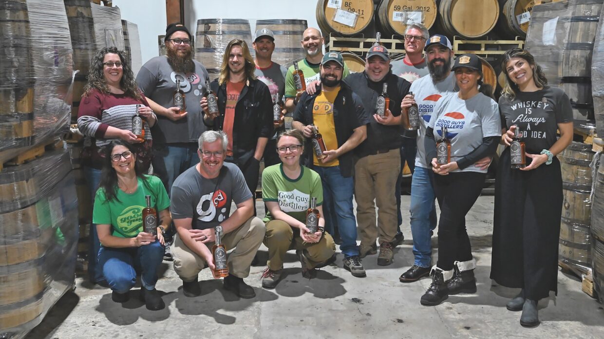 People in a distillery holding whiskey bottles